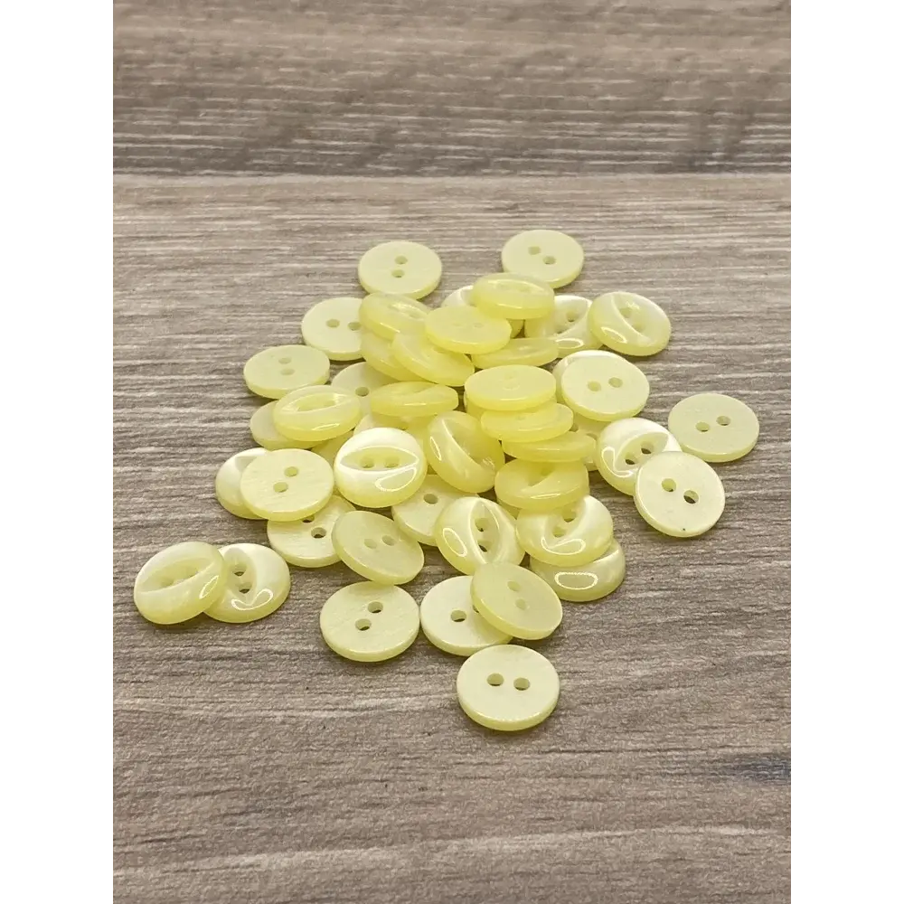 Pile of pale yellow two-hole buttons.