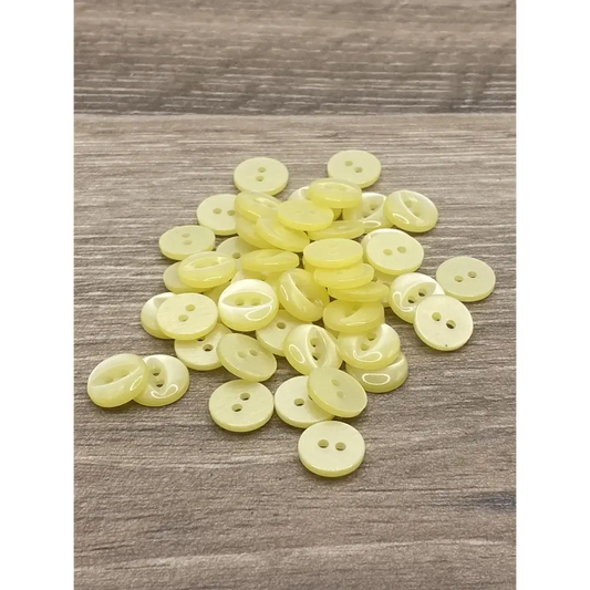 Pile of pale yellow two-hole buttons.