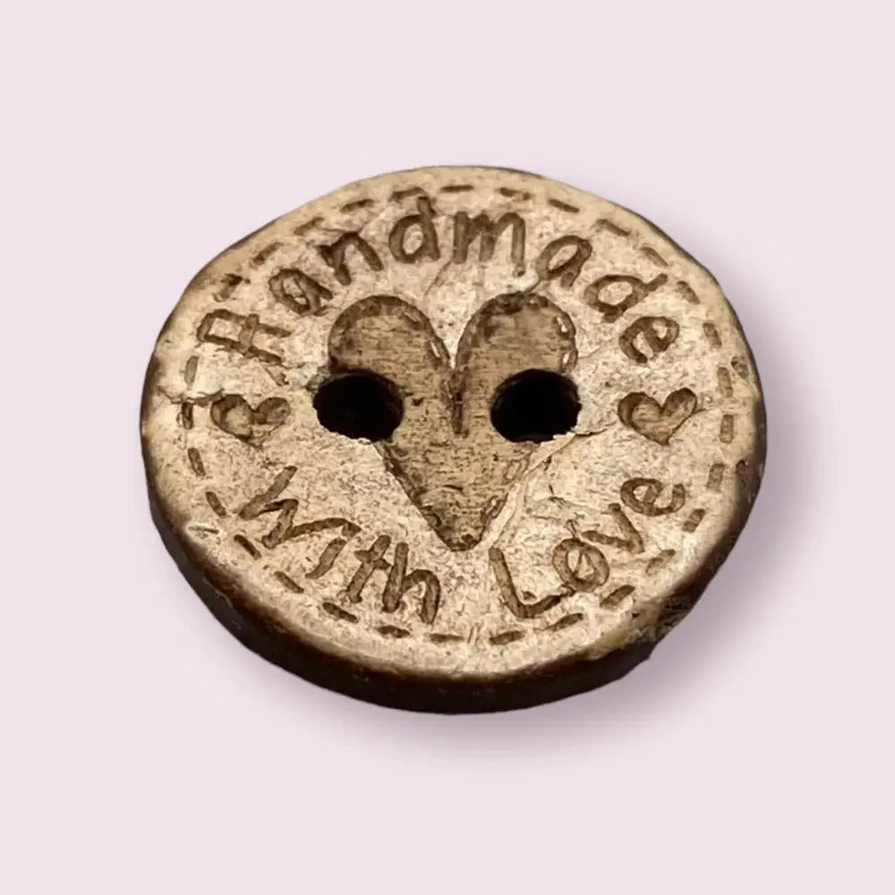Round wooden button with heart and text.