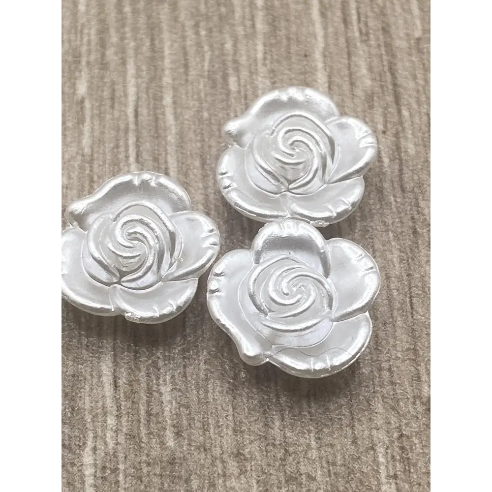 Three silver rose-shaped buttons.