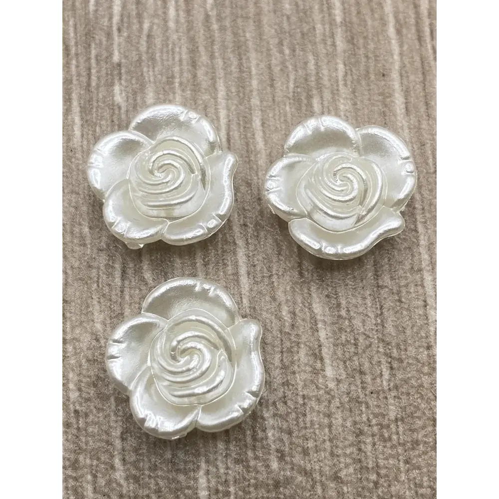 Three pearlescent rose embellishments.