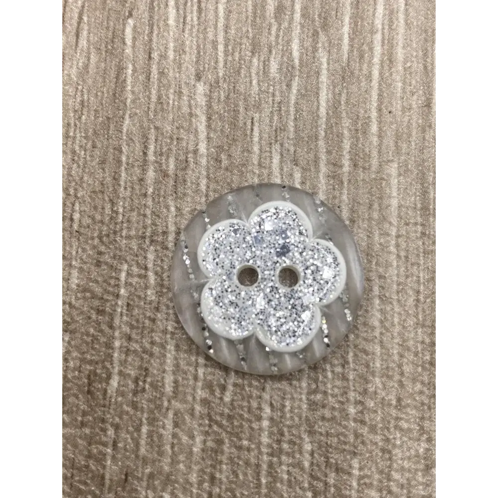 Round, gray button with a glittery flower design.