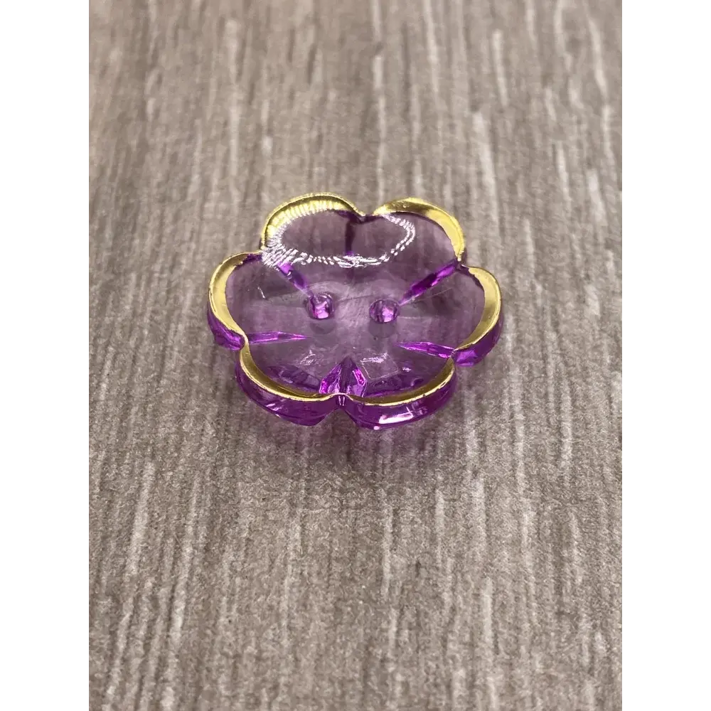Purple flower-shaped button with gold trim.