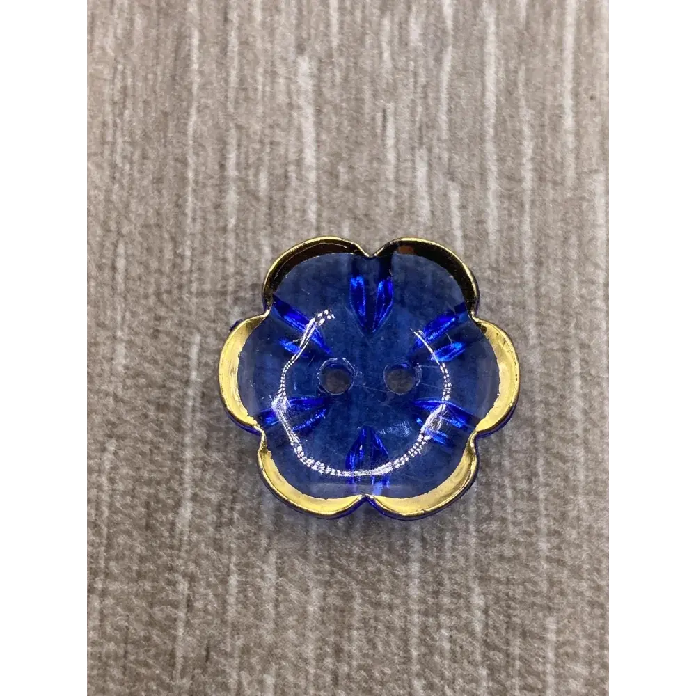 Blue flower-shaped button with gold trim.
