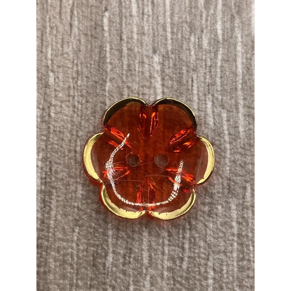 Orange flower-shaped button with gold trim.