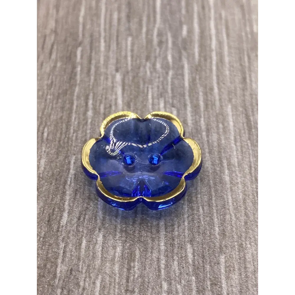 Blue flower-shaped button with gold trim.