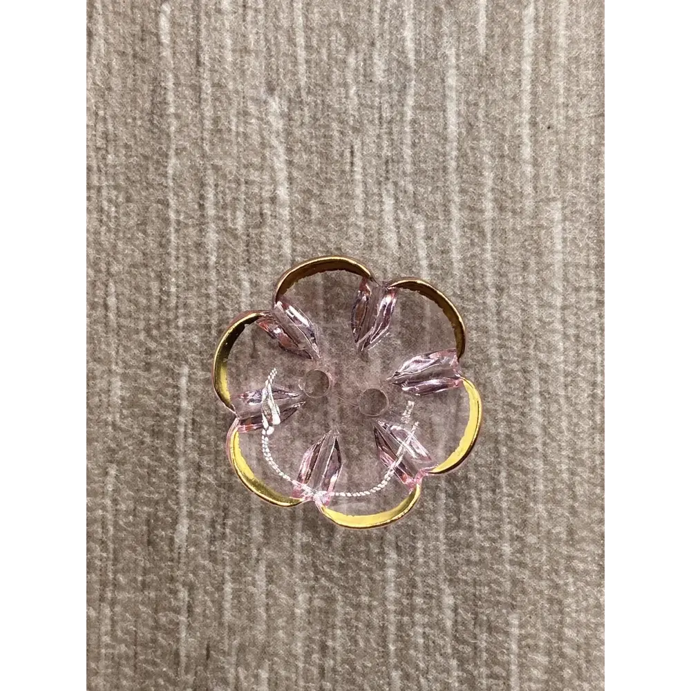 Flower-shaped, pink and gold button.