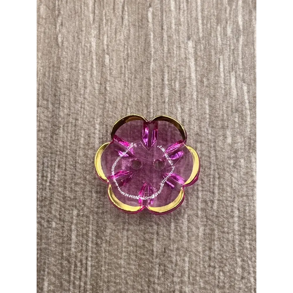 Translucent pink flower-shaped button with gold trim.