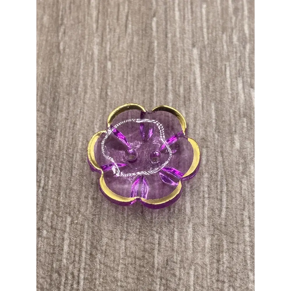 Purple flower-shaped button with gold trim.