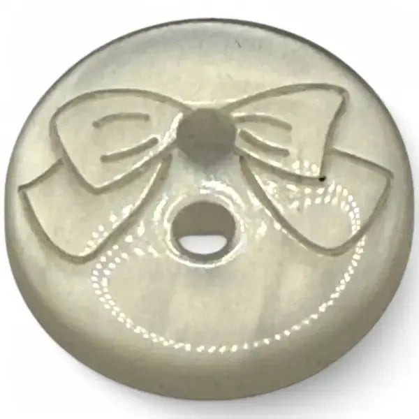Round, pearlescent button with a bow design.