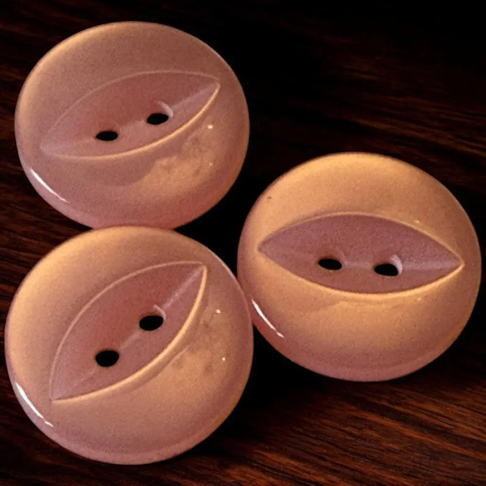 Three pink, round, two-hole buttons.