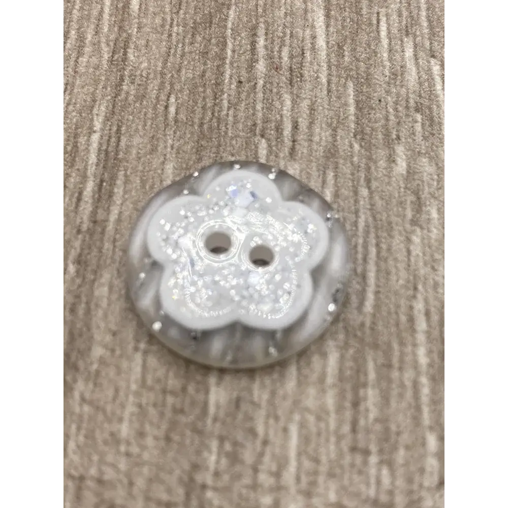 White flower-shaped button with glitter.