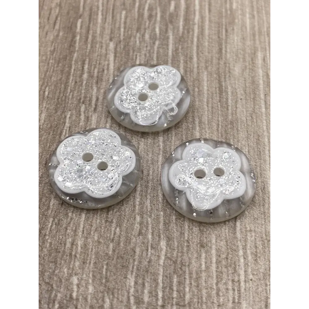 Three flower-shaped, two-hole buttons with glitter.