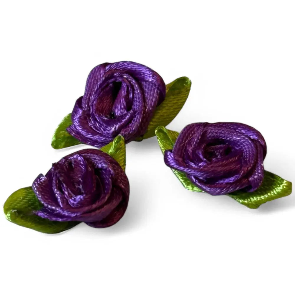 Three purple ribbon roses with green leaves.