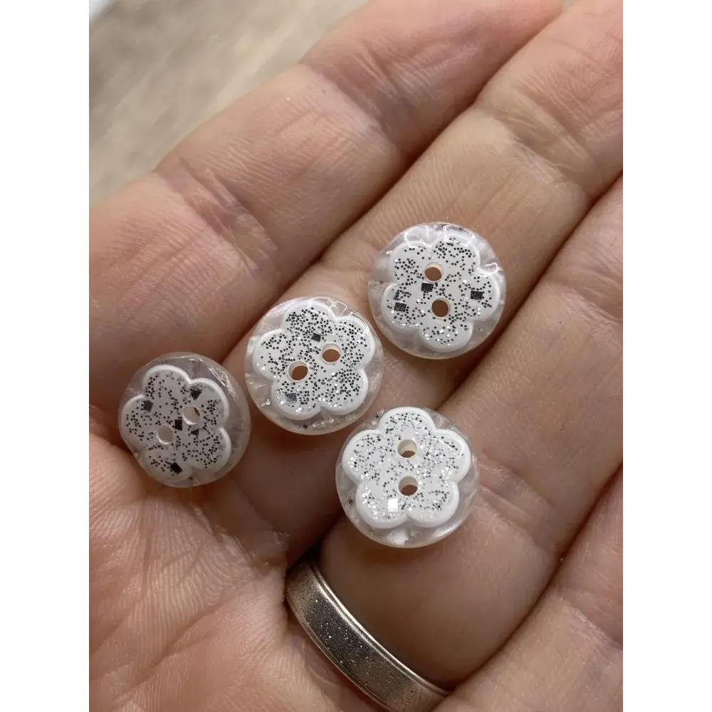 Five flower-shaped, clear buttons with glitter.