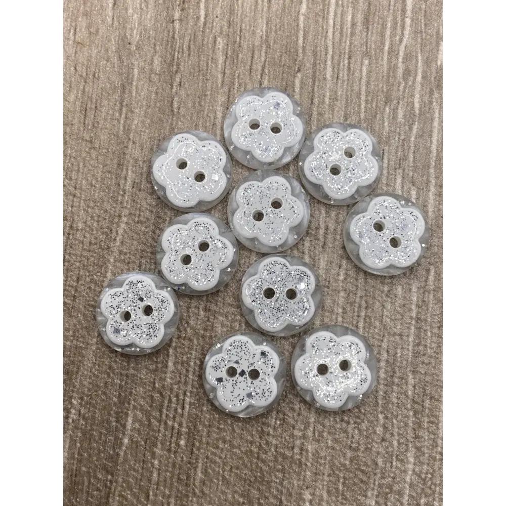 Ten flower-shaped, glittery white buttons.