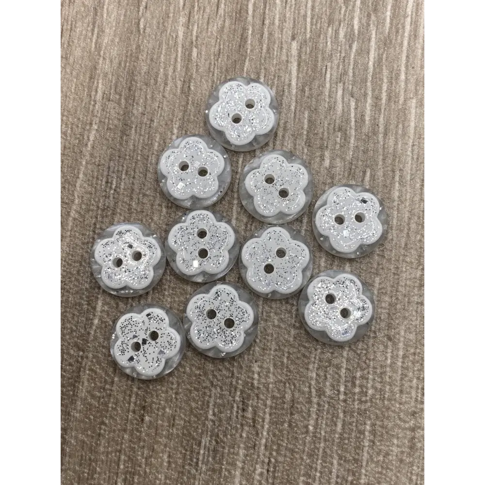 Ten flower-shaped, glittery, three-hole buttons.