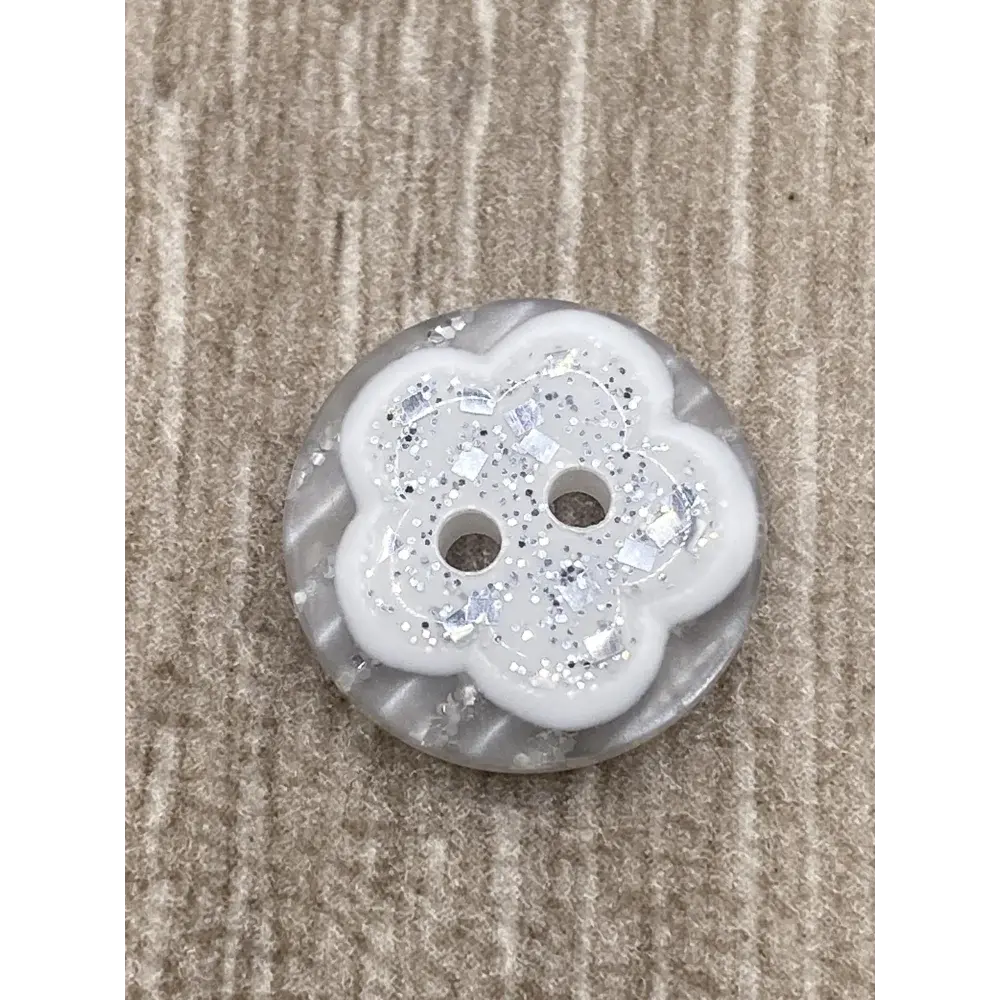 White flower-shaped button with glitter.