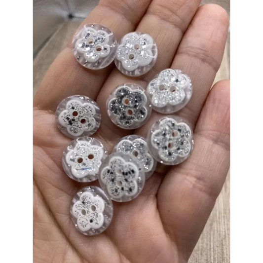 Handful of flower-shaped glitter buttons.