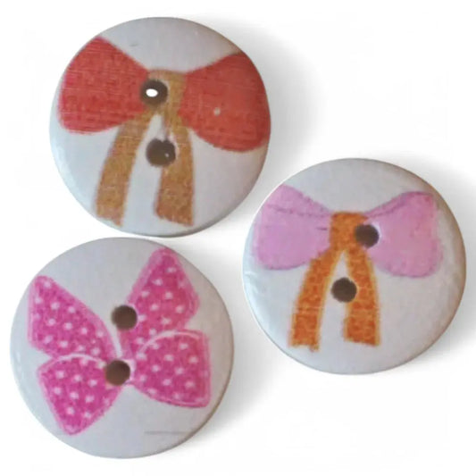 Three round buttons with bow designs.