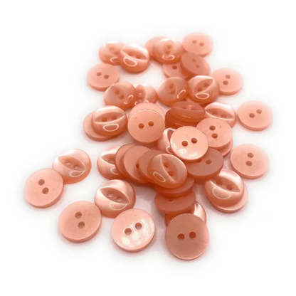 Pile of peach-colored, two-hole buttons.