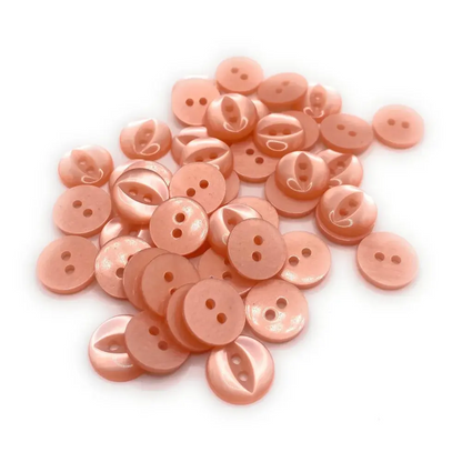 Pile of peach-colored, two-hole buttons.