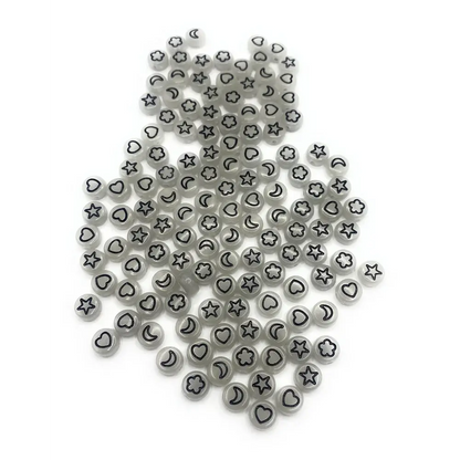 Pile of gray beads with black celestial and heart designs.