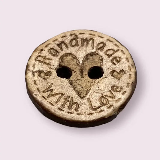 Round wooden button with heart and text.