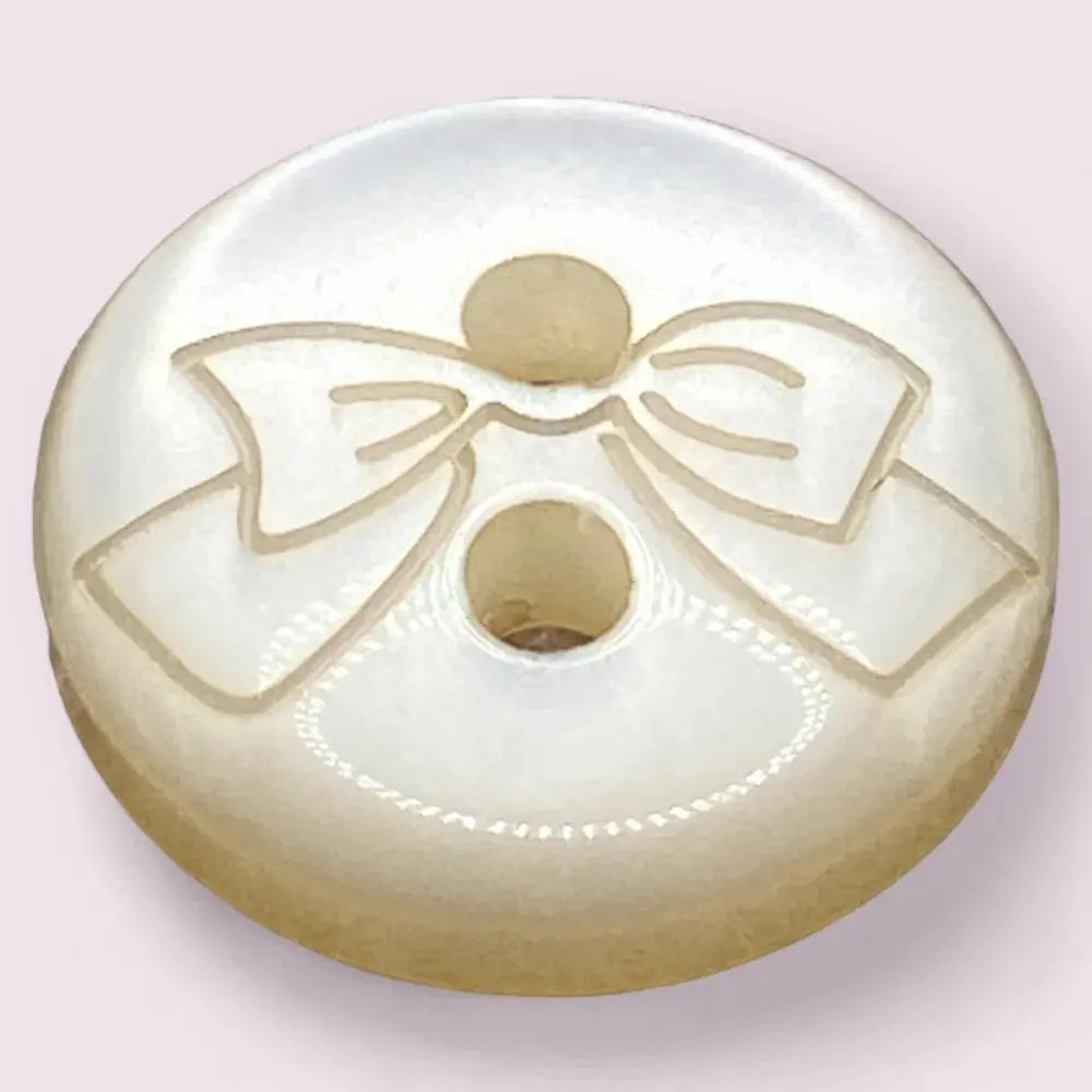Round, pearlescent button with a bow design.
