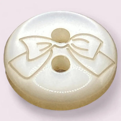 Round, pearlescent button with a bow design.
