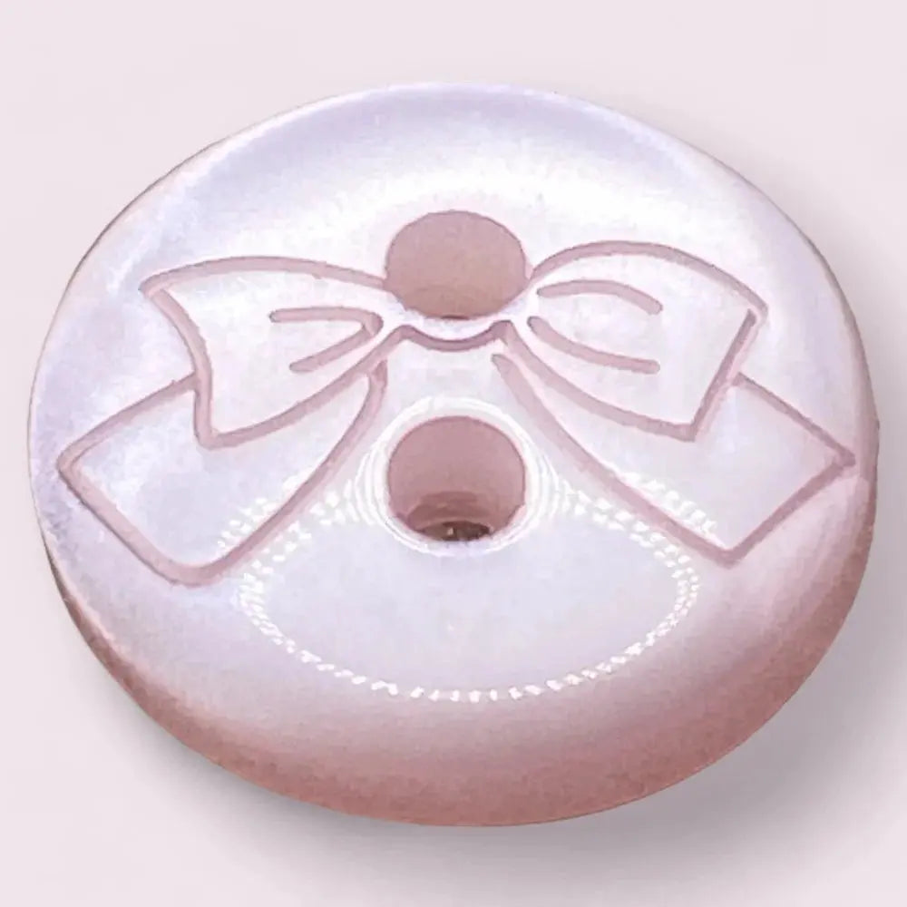 Round, pink button with bow design.