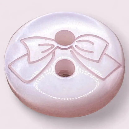 Round, pink button with bow design.