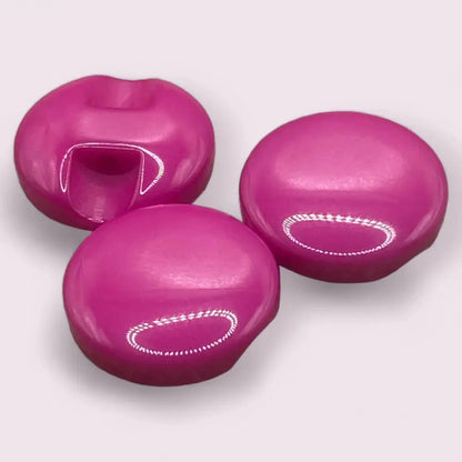 Three glossy pink lip-shaped and round candies.