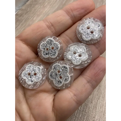 Handful of flower-shaped glitter buttons.