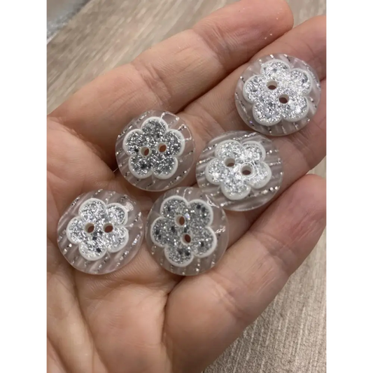 Handful of flower-shaped glitter buttons.