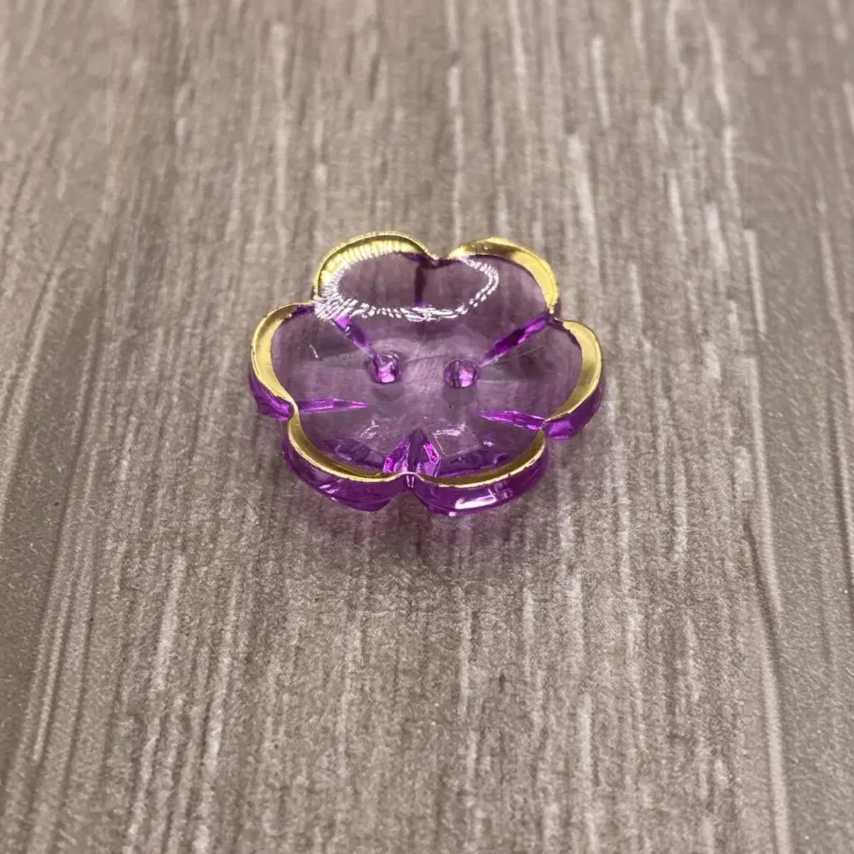 Purple flower-shaped button with gold trim.