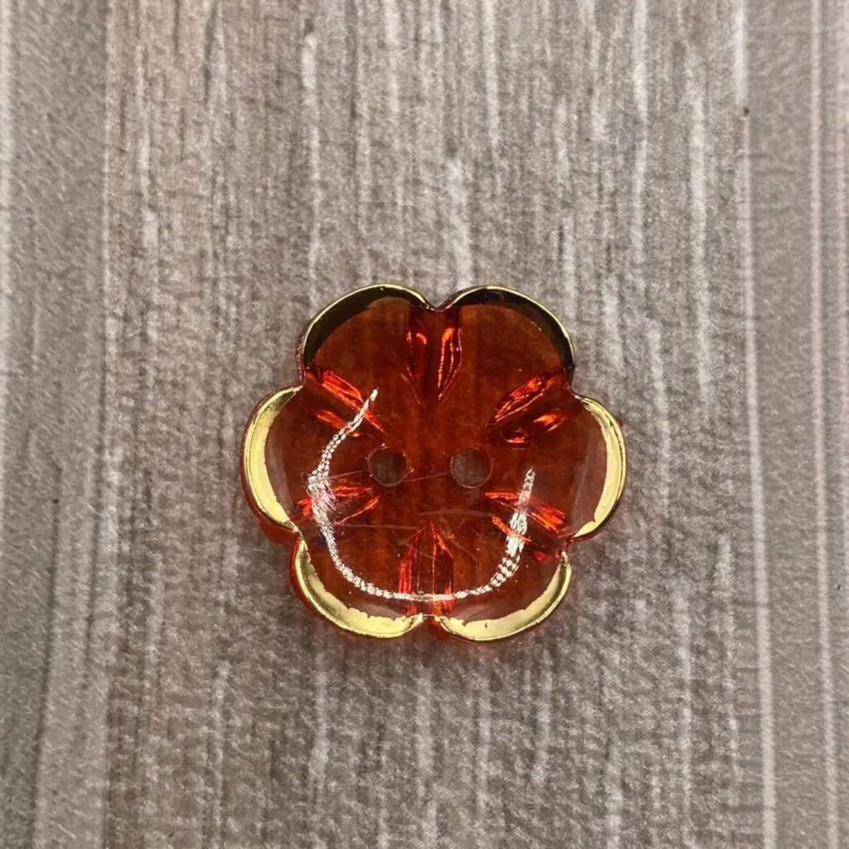 Orange flower-shaped button with gold trim.