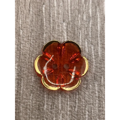 Orange flower-shaped button with gold trim.