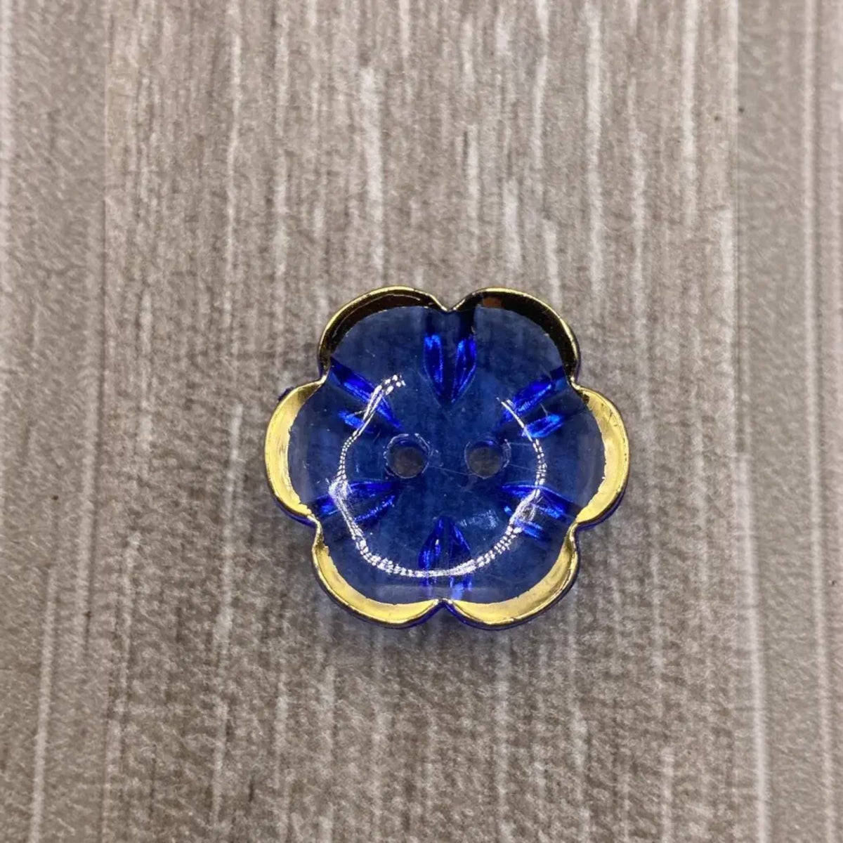 Blue flower-shaped button with gold trim.