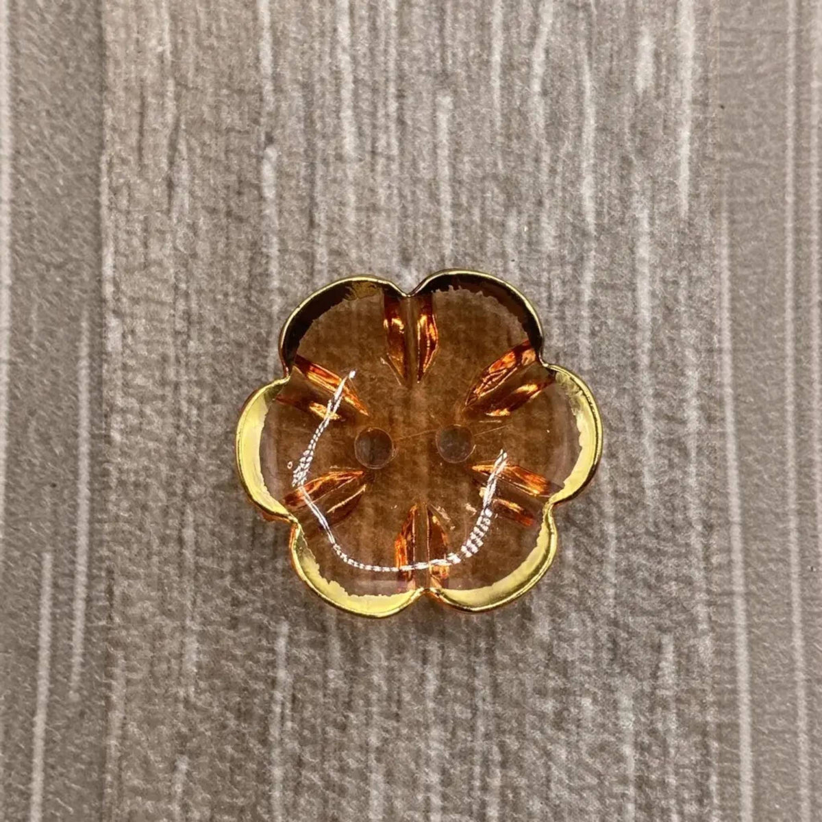 Brown flower-shaped button with gold trim.