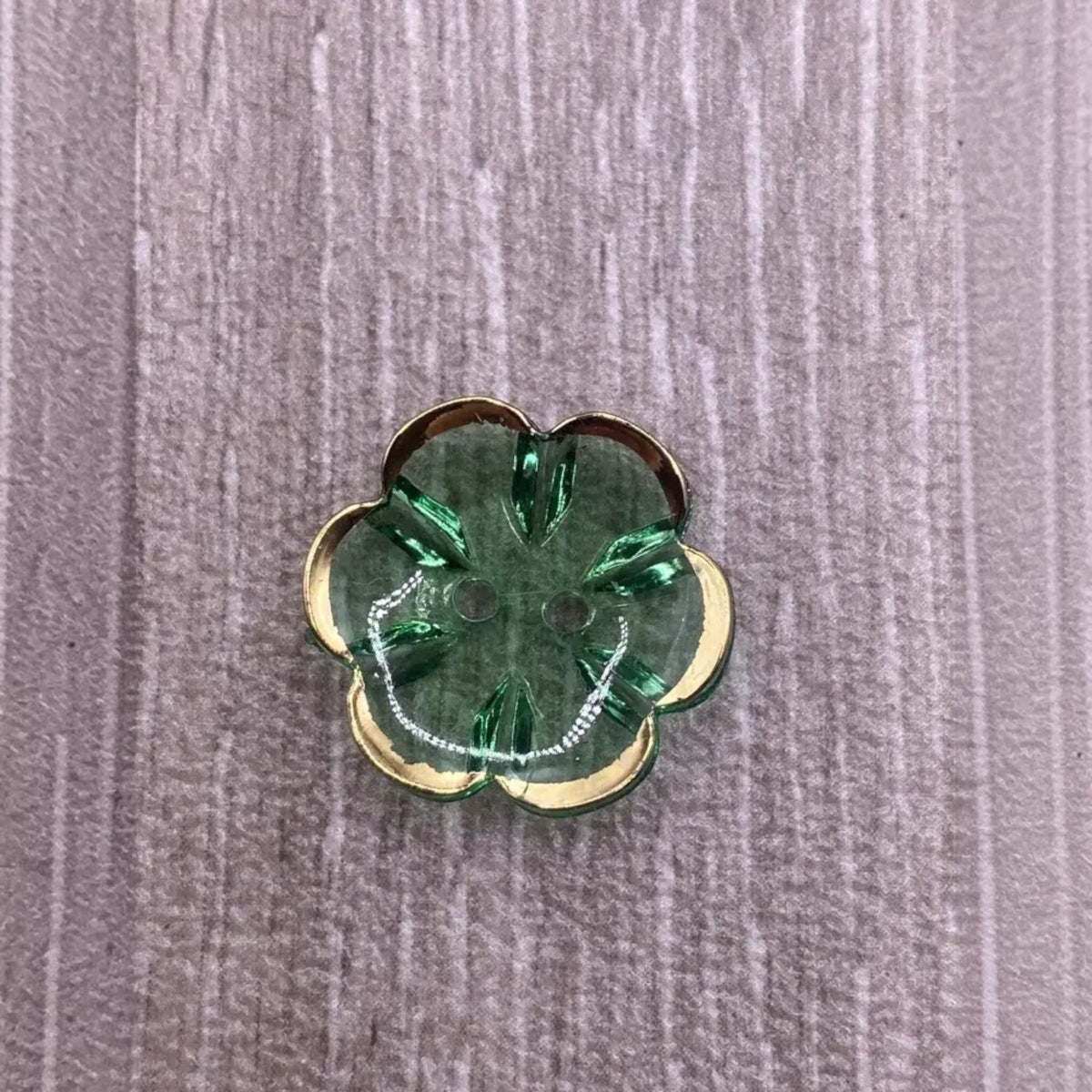 Green flower-shaped button with gold trim.