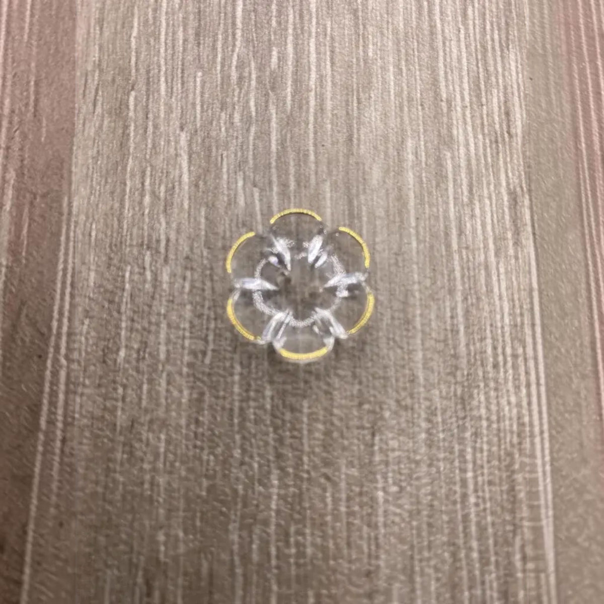 Clear flower-shaped button with yellow trim.