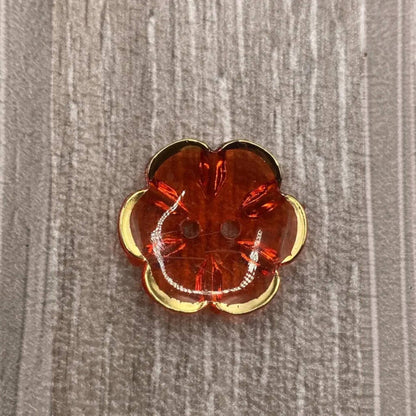 Orange flower-shaped button with gold trim.