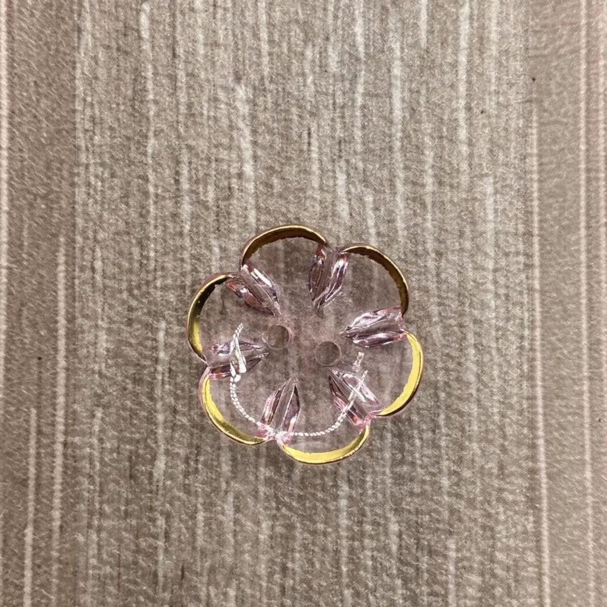 Flower-shaped, pink and gold button.