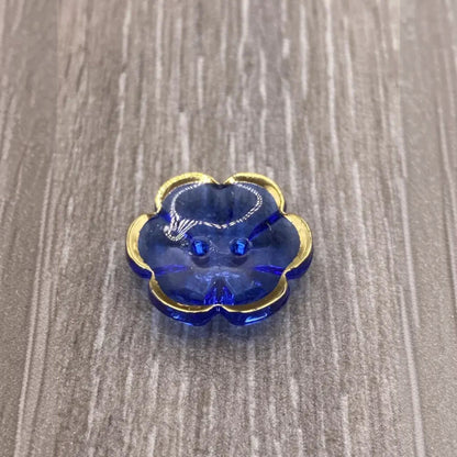 Blue flower-shaped button with gold trim.
