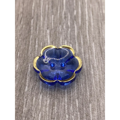 Blue flower-shaped button with gold trim.