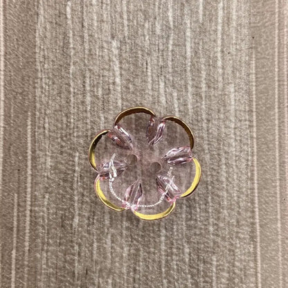 Flower-shaped, pink and gold button.