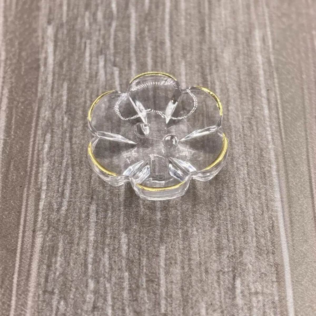 Clear glass flower-shaped dish with gold trim.