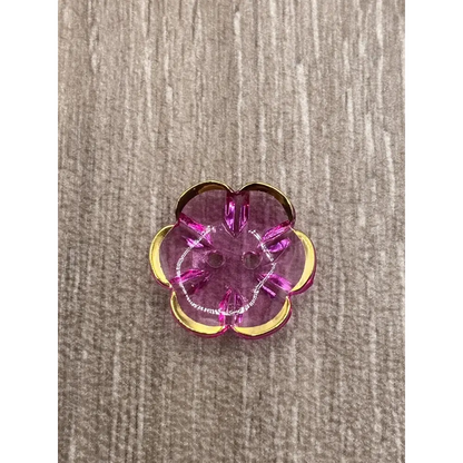 Translucent pink flower-shaped button with gold trim.