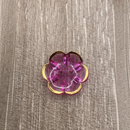 Translucent pink flower-shaped button with gold trim.